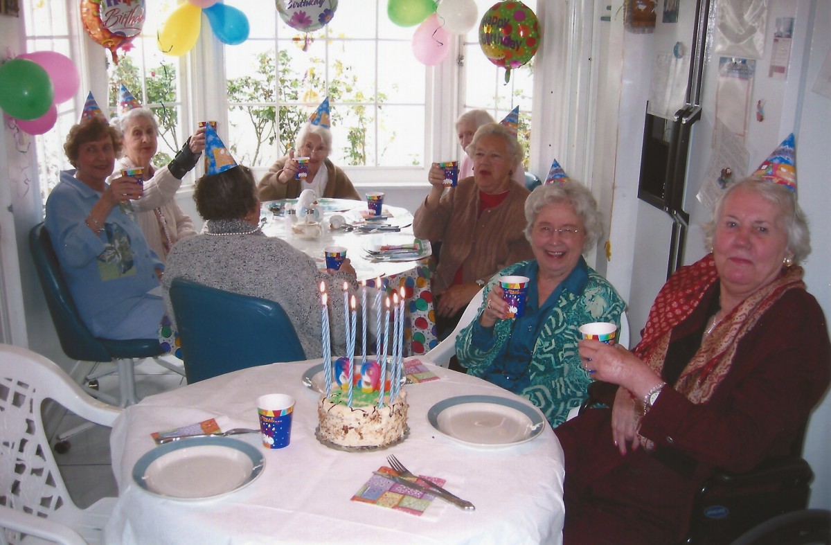 A group of elderly people celebrating a birthday with cake and decorations.