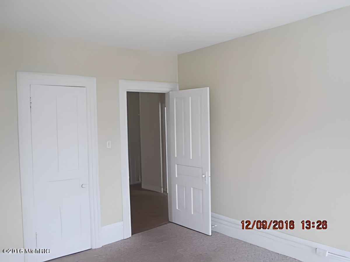 An empty room with beige walls and a closed closet door.
