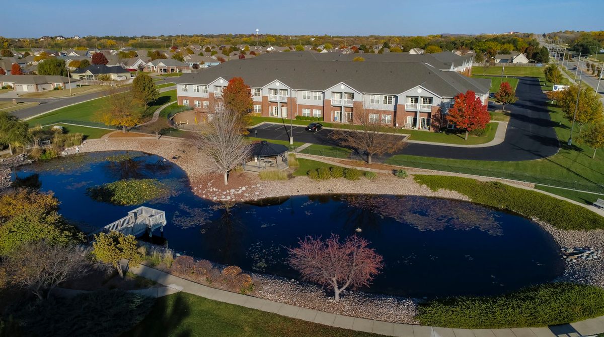 Aerial view of a residential area with a pond and surrounding landscape.