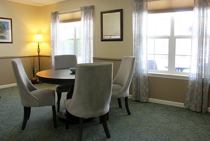 A cozy dining room with a round table and chairs next to large windows.