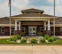 A front view of a building with columns, landscaping, and flags.