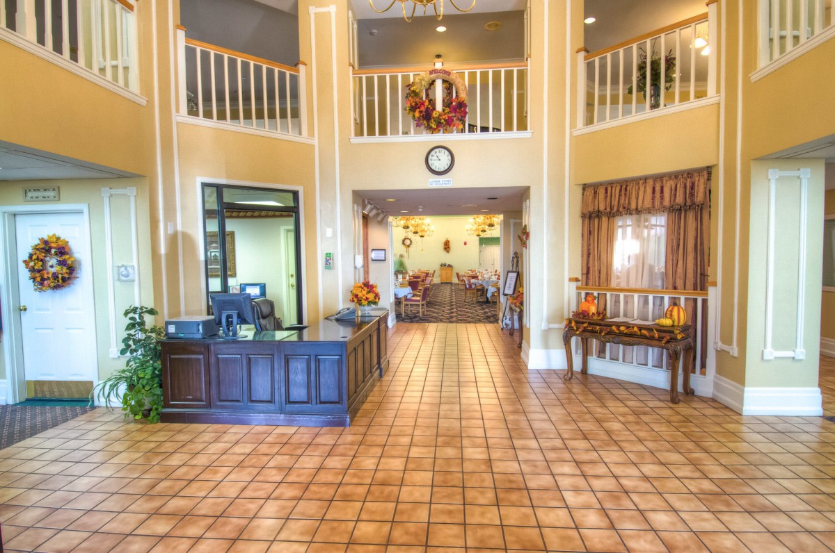 A spacious and warmly decorated lobby with a reception desk and tile flooring.