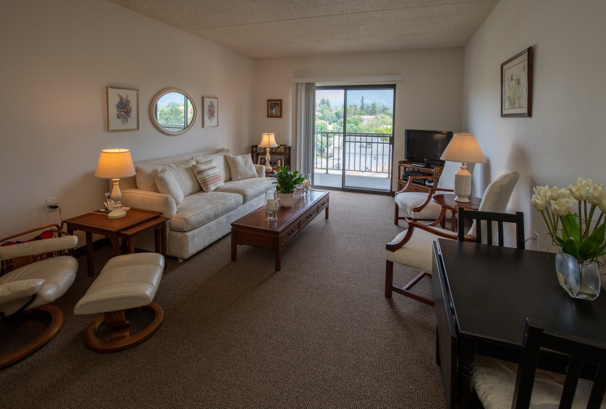 A cozy living room with a sofa, coffee table, and warm lighting, complemented by a balcony view.