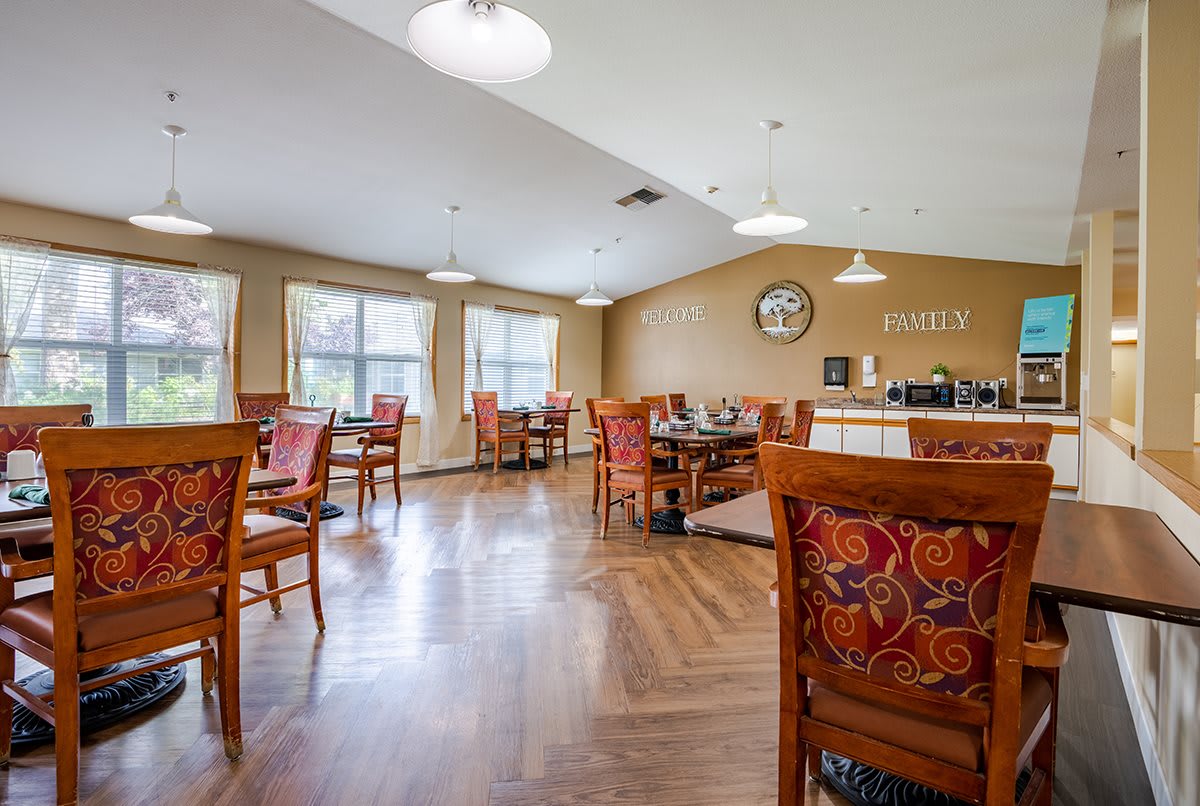 A cozy dining area with neatly arranged tables and chairs, featuring warm lighting and elegant decor.