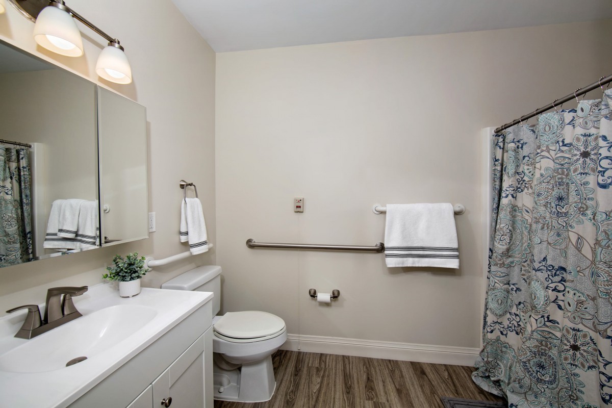 A modern bathroom with a toilet, sink, and a shower area featuring a patterned curtain.