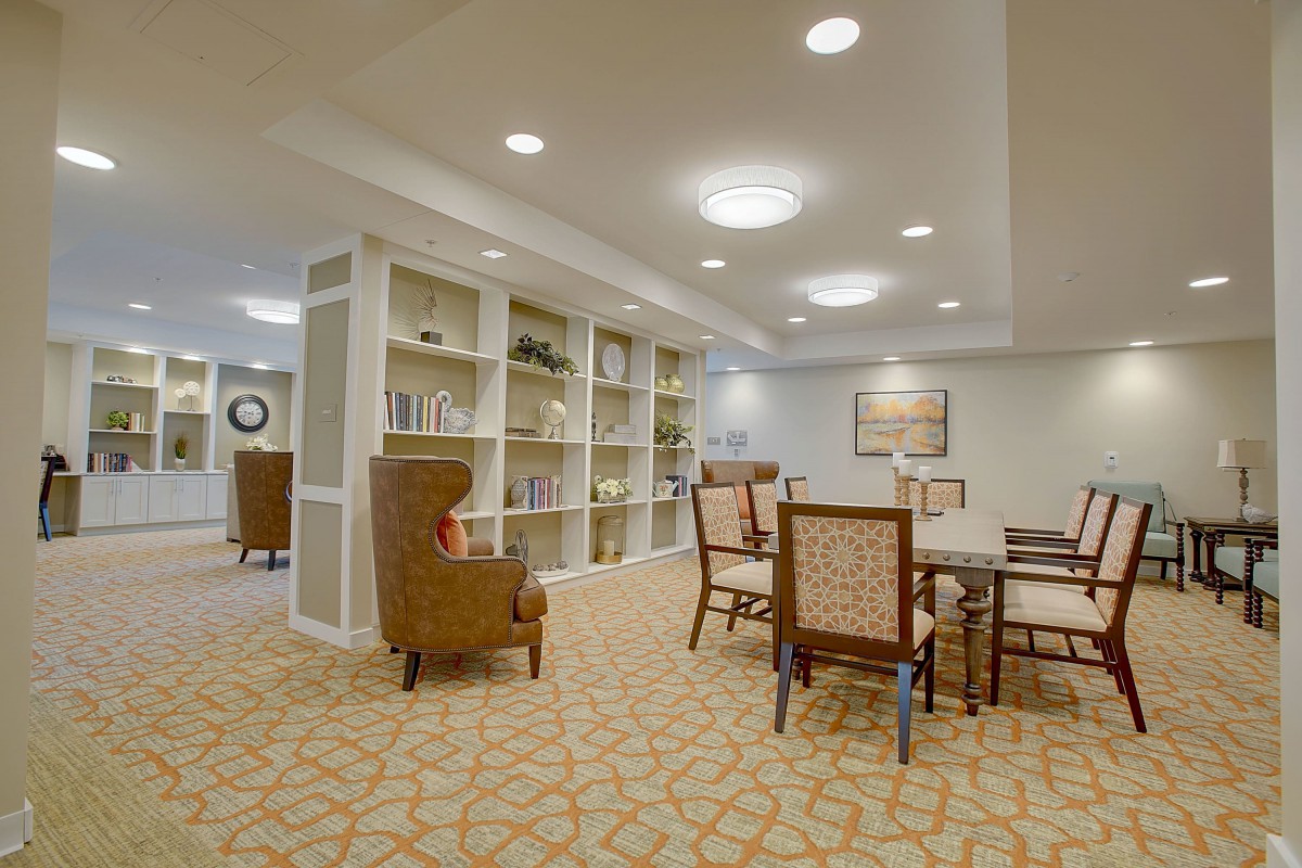 A spacious and well-lit living room with bookshelves and a dining area.
