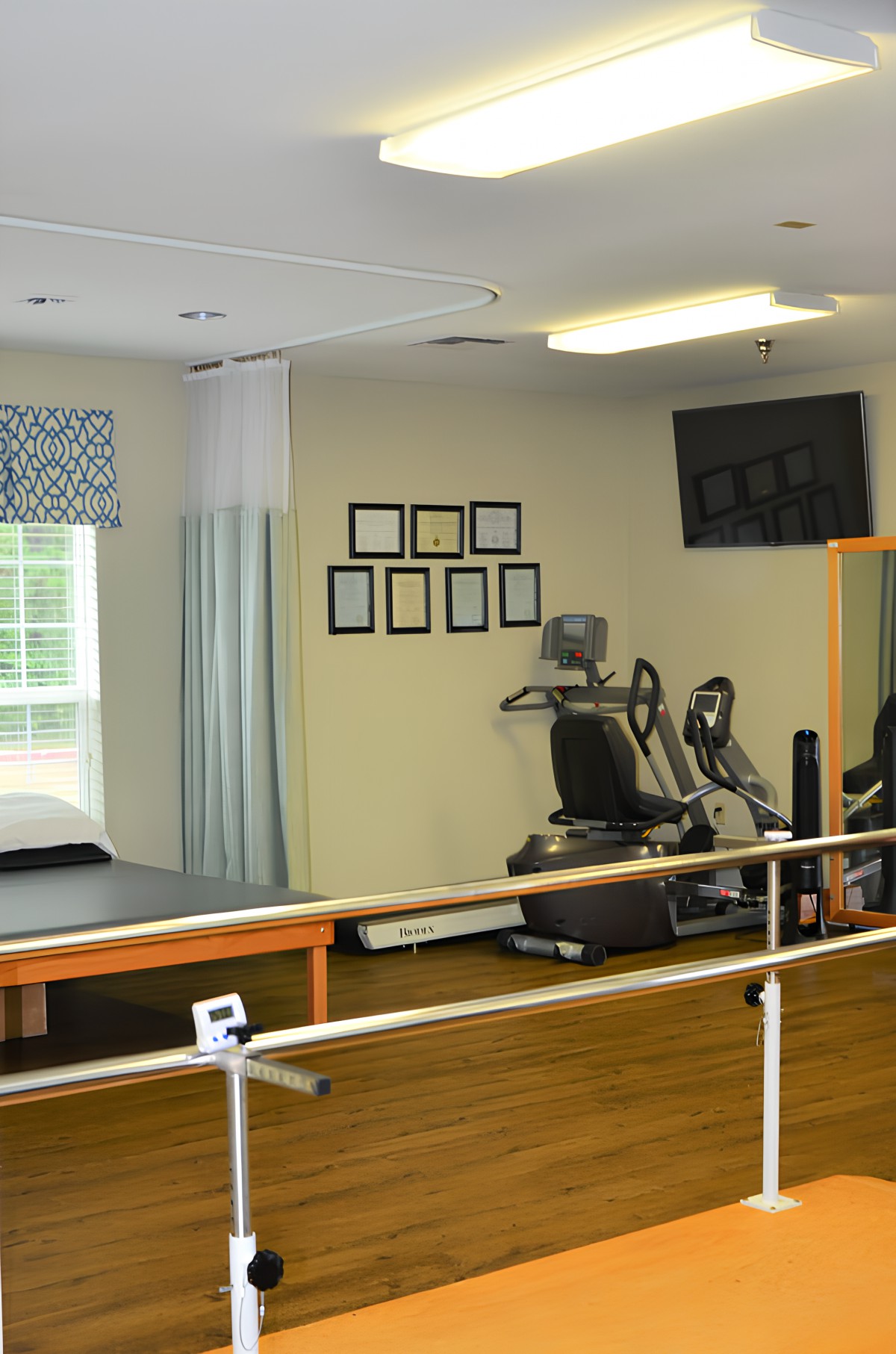A rehabilitation room equipped with exercise machines and parallel bars for physical therapy.