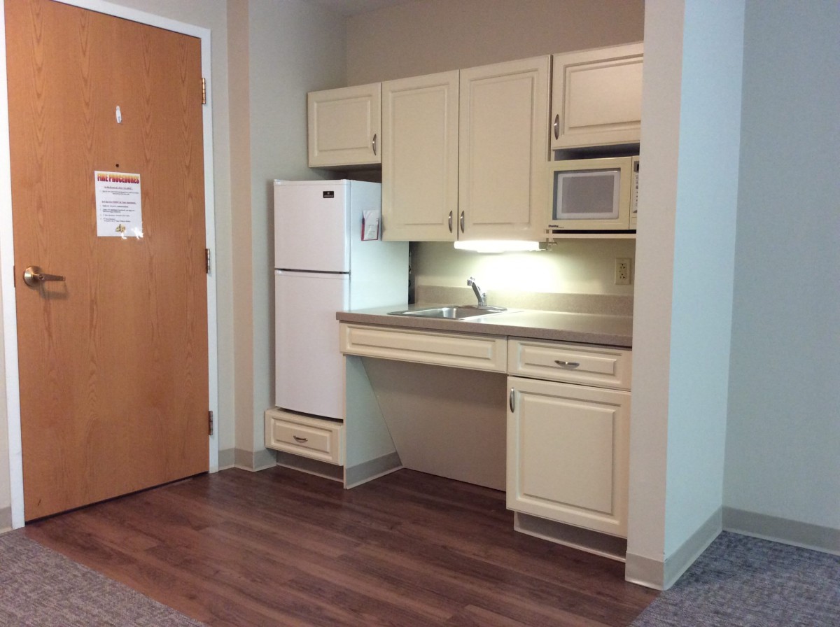 A small kitchenette setup with a fridge, sink, and microwave.
