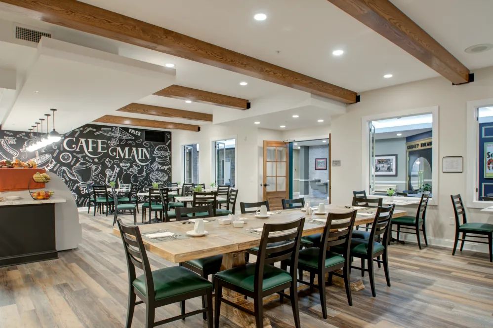 A modern restaurant interior with wooden beams and neatly arranged tables and chairs.