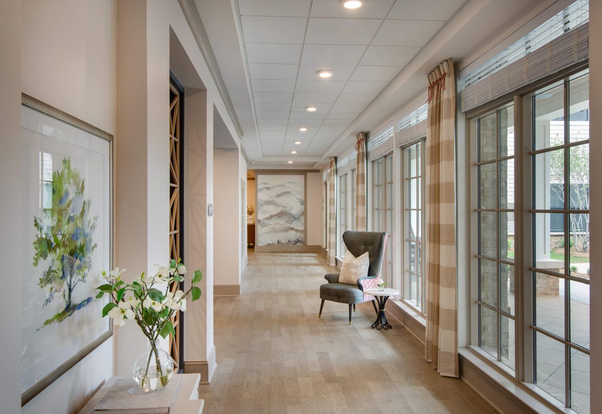 A modern hallway featuring large windows, comfortable seating, and elegant decor.