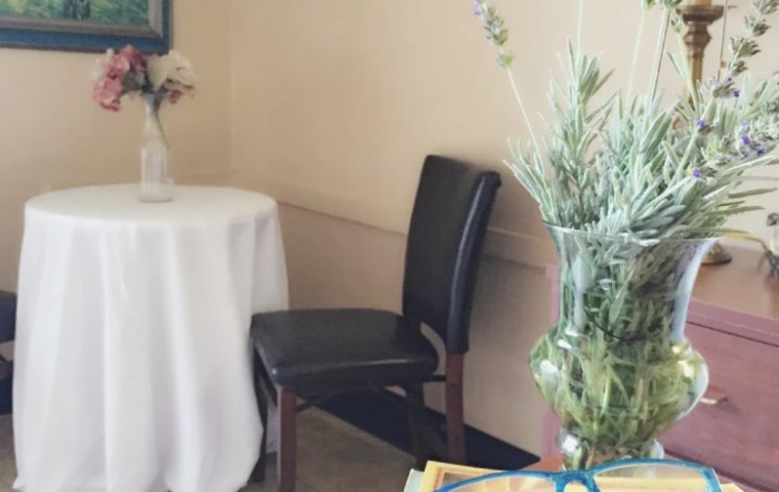 A cozy corner with a table, chair, and decorative plants.