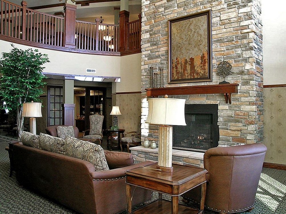 A cozy lounge area featuring a stone fireplace, comfortable sofas, and elegant table lamps.