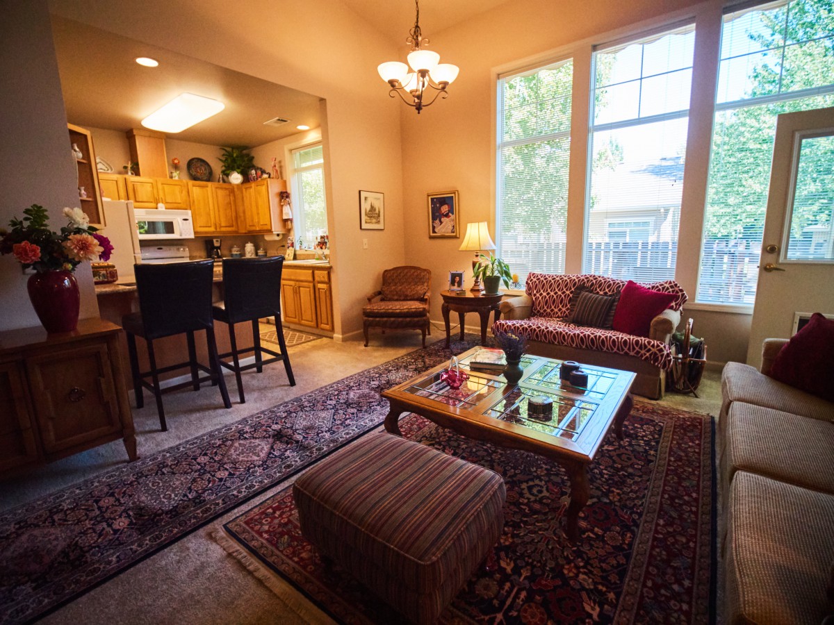 A cozy living room with an open kitchen and warm lighting.