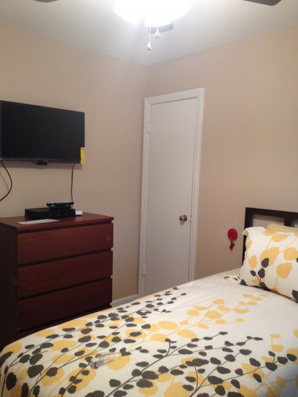 A cozy bedroom with a wall-mounted TV and a neatly arranged bed.