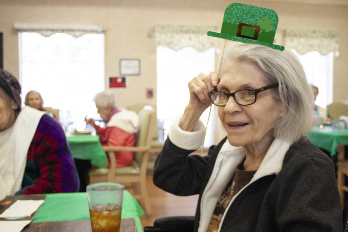 A senior woman enjoying St. Patrick's Day festivities, wearing a playful green hat.