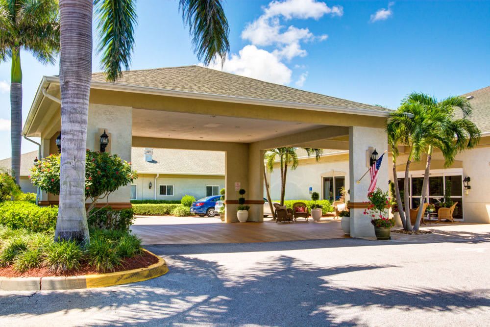 A sunny entrance to a tropical building with palm trees and a covered walkway.