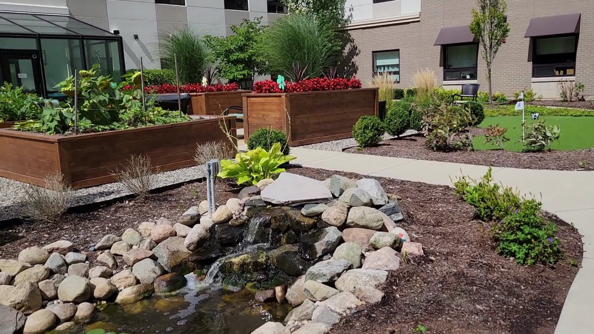 A beautifully landscaped garden with a small pond surrounded by rocks and vibrant flower beds.