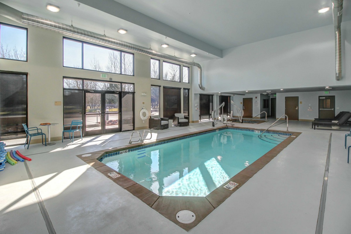 A bright indoor swimming pool area with large windows.