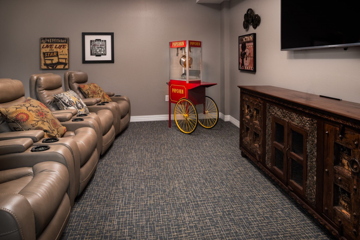 A cozy home theater with leather recliners and a popcorn machine.