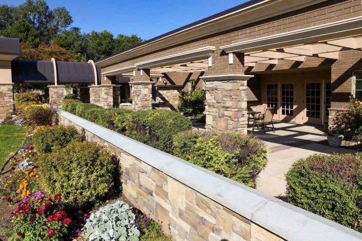 Modern building with stone columns and lush landscaping.
