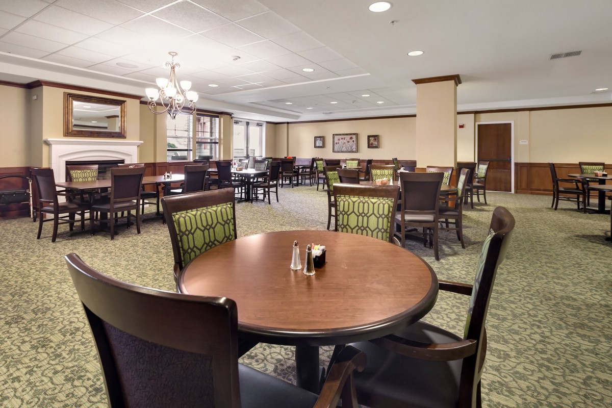 A spacious dining area with neatly arranged tables and chairs, featuring elegant lighting fixtures.