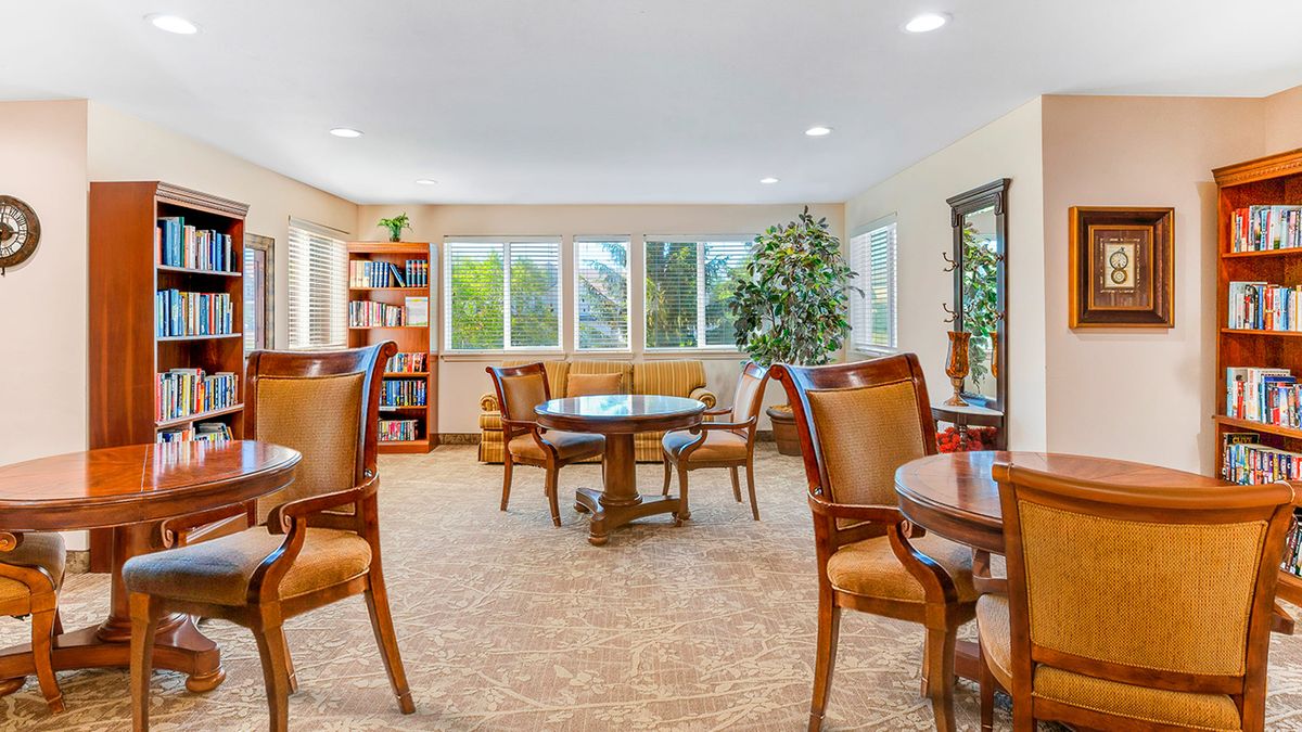 A cozy lounge area with elegant wooden furniture and large windows providing a bright atmosphere.