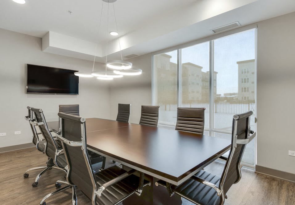 A modern conference room with a large table, sleek chairs, and ample natural light.