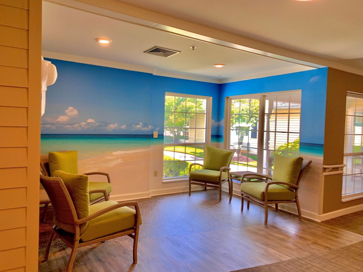 A bright and inviting waiting room with green chairs and a beach-themed wall mural.