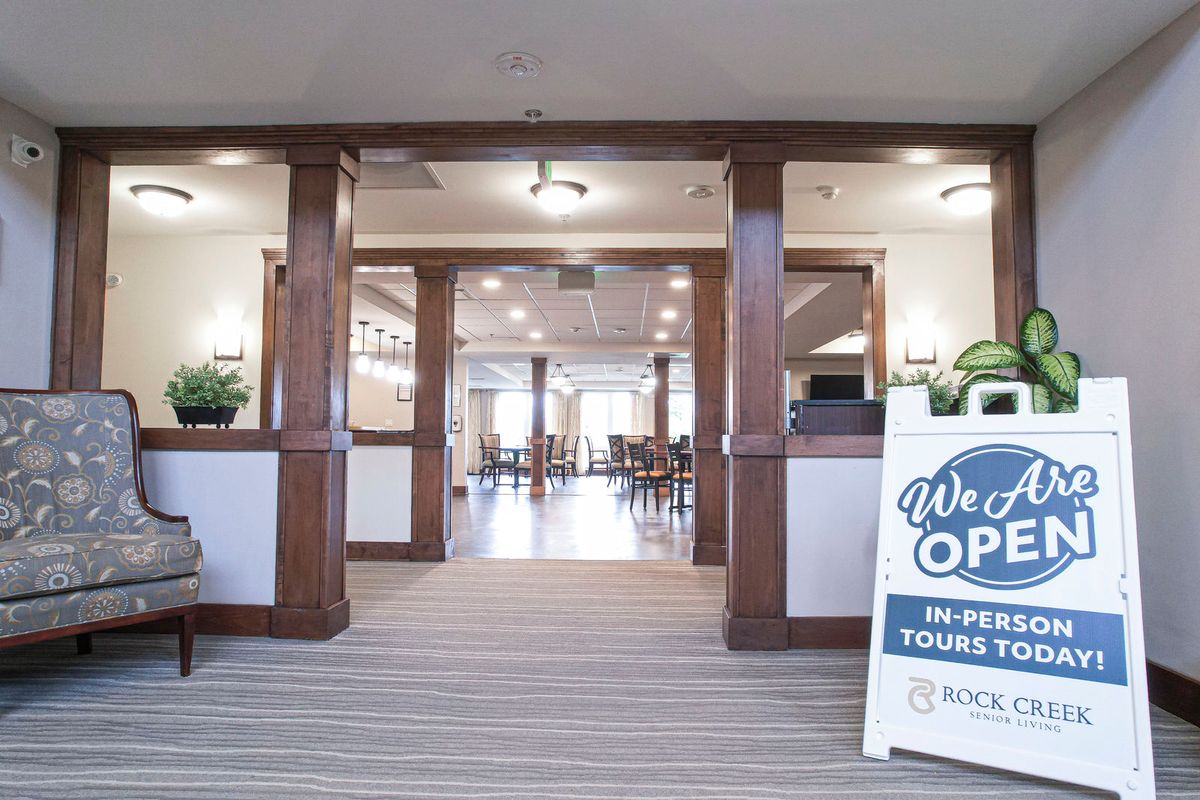 A welcoming lobby area with an open sign and wooden pillars leading to a spacious room.