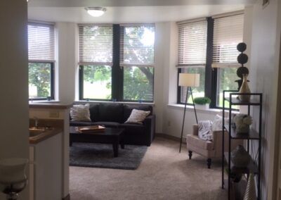 A cozy living room with a sofa, armchair, and large windows.