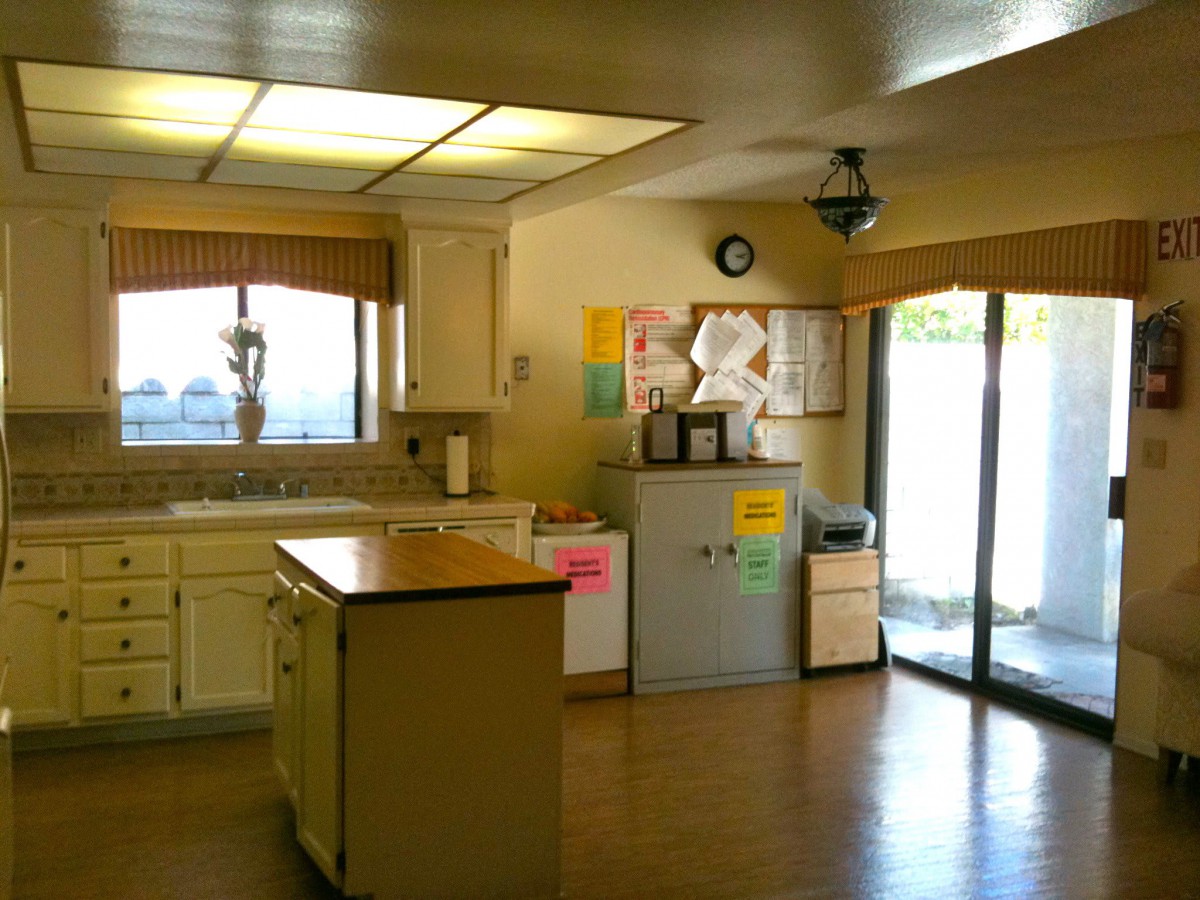 A bright kitchen interior featuring a central island and wooden flooring.