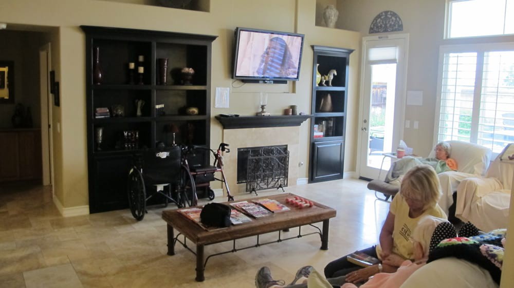 A cozy living room with a television above the fireplace, surrounded by shelves and a bicycle leaned against the wall.