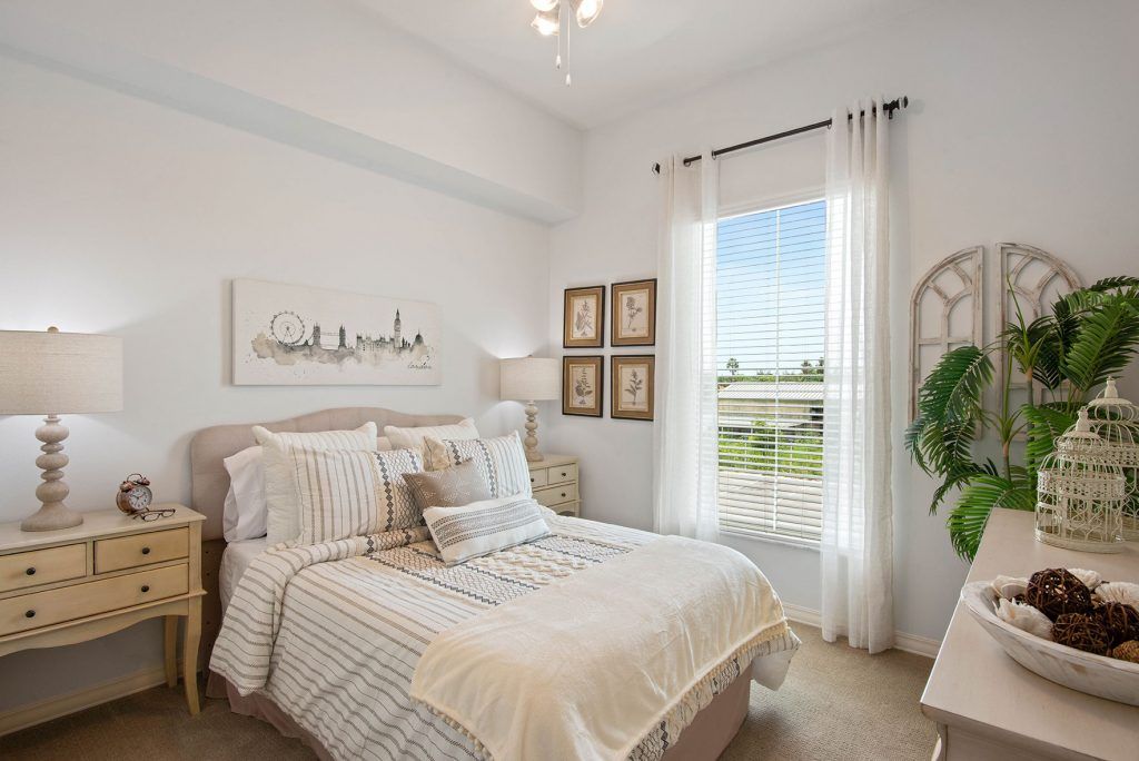 A bright and cozy bedroom with minimalist decor, featuring a neatly made bed and sunlight streaming through the window.