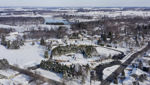 A serene winter landscape blanketed in snow, showcasing an aerial view of a rural area with winding roads and a river.