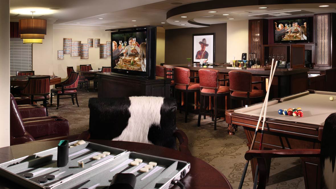 A cozy bar lounge featuring a cowhide chair, backgammon table, and a television.