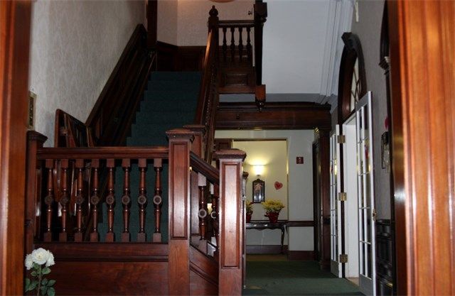 An interior view of a historic building featuring a wooden staircase and hallway.
