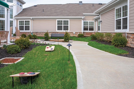 A well-maintained outdoor space featuring a concrete pathway, grassy areas, and recreational games.