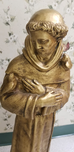A beautifully crafted golden statue of a monk holding birds.