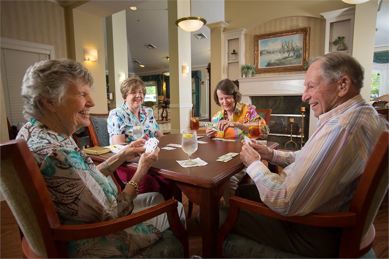 A group of seniors enjoying a card game at a table indoors.