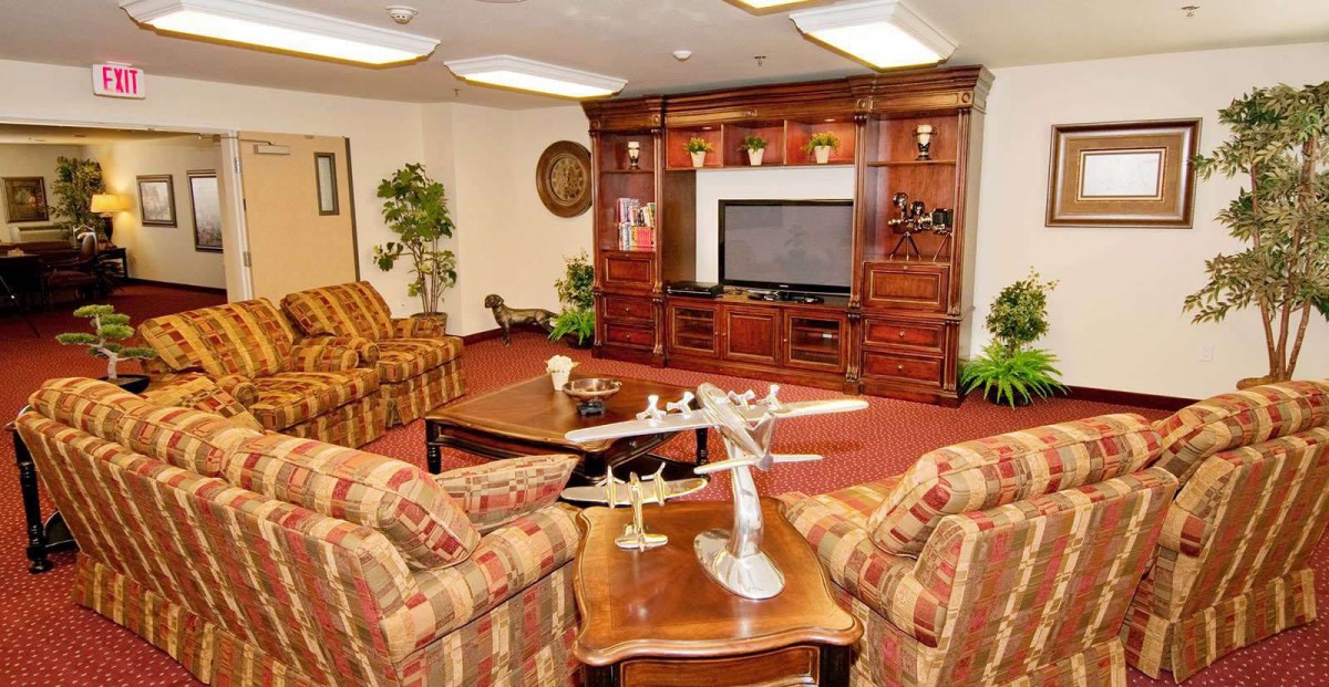 A cozy living room with a wooden entertainment center, plush sofas, and decorative plants.