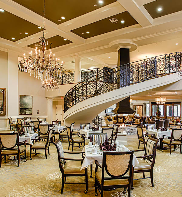 A luxurious restaurant interior featuring elegant chandeliers and a grand staircase.