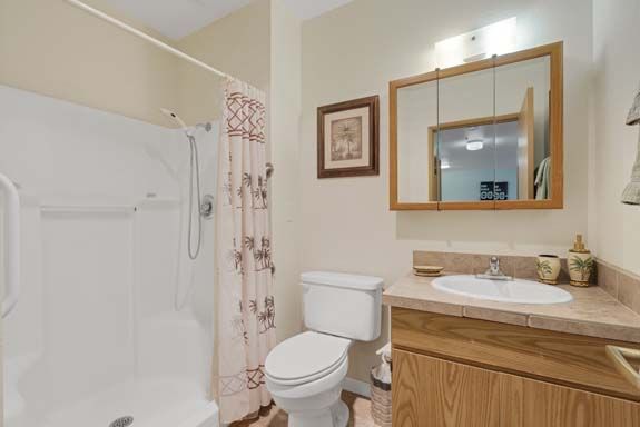 A neatly arranged bathroom with a shower, toilet, and wooden cabinet.