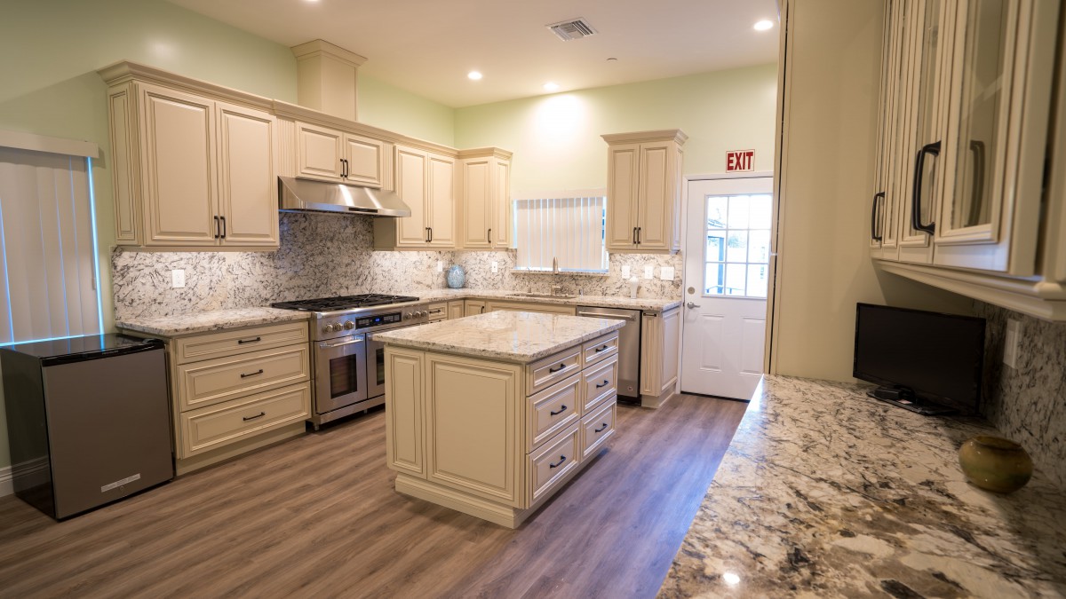A modern kitchen with an island, cream cabinets, and hardwood flooring.