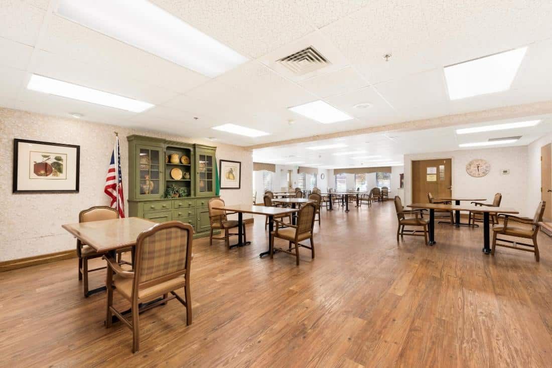 A spacious dining area with wooden floors and several tables and chairs.