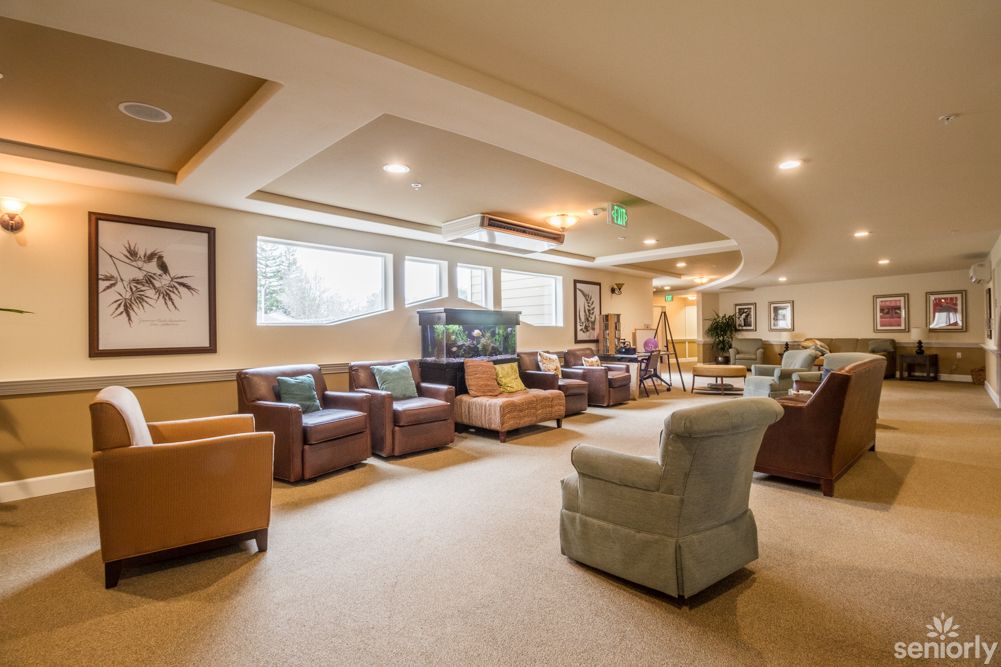 A spacious and cozy living room with multiple sofas and armchairs, featuring warm lighting and decorative elements.
