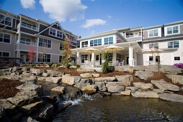 A modern residential building with landscaped gardens and a water feature.