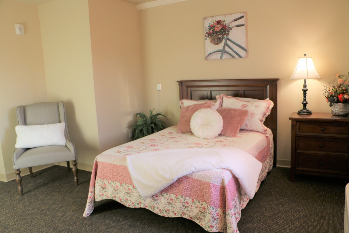 A cozy bedroom with a neatly made bed, soft pink and beige tones, and elegant decor.