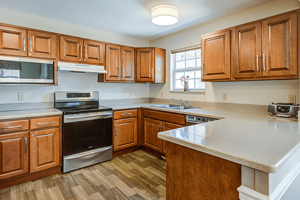 A modern kitchen with wooden cabinets, a stove, oven, and ample countertop space.