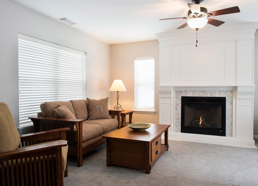 A cozy living room with a sofa, wooden coffee table, lamp, and a fireplace.