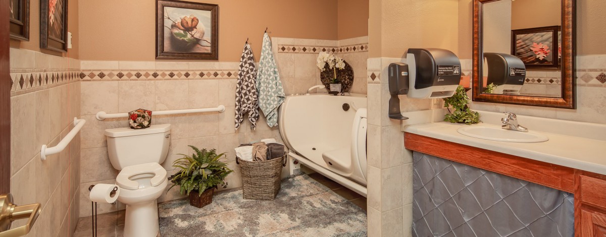 A cozy bathroom featuring an accessible bathtub, with decorative towels and plants adding a touch of warmth.